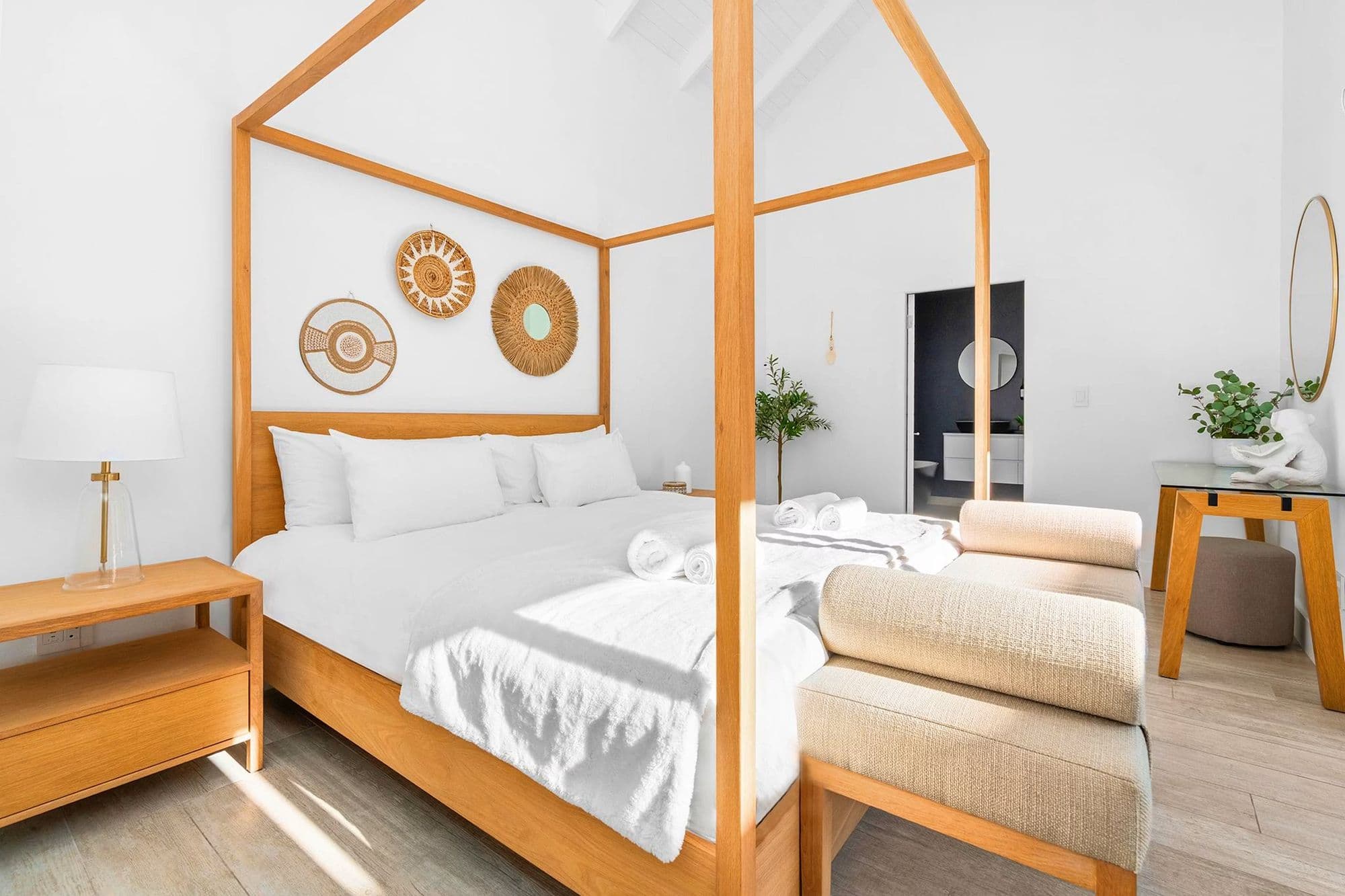 A four-poster bed in reclaimed timber, styled with woven textures