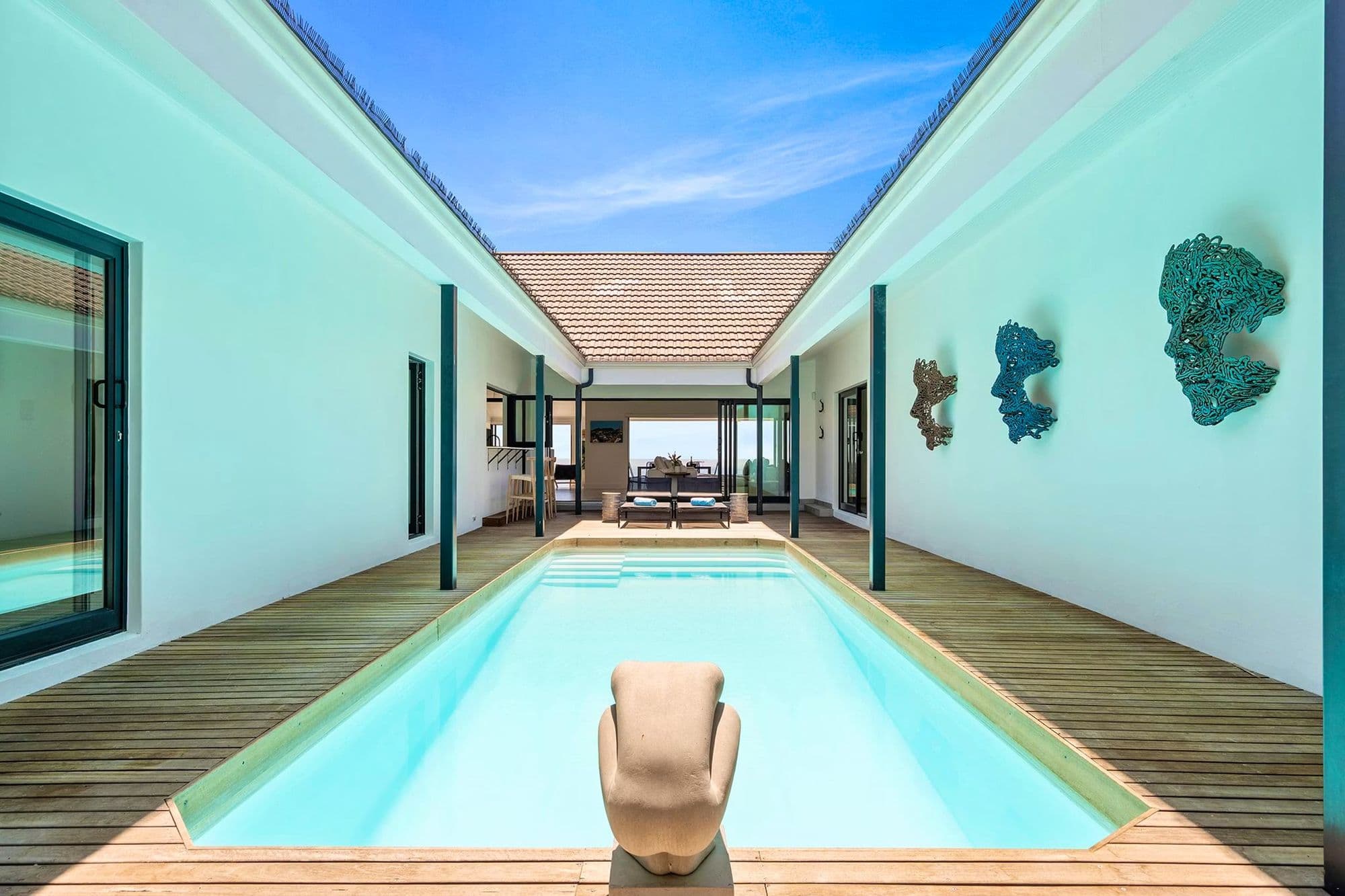A long courtyard lap pool at Villa View, framed by coral wall art