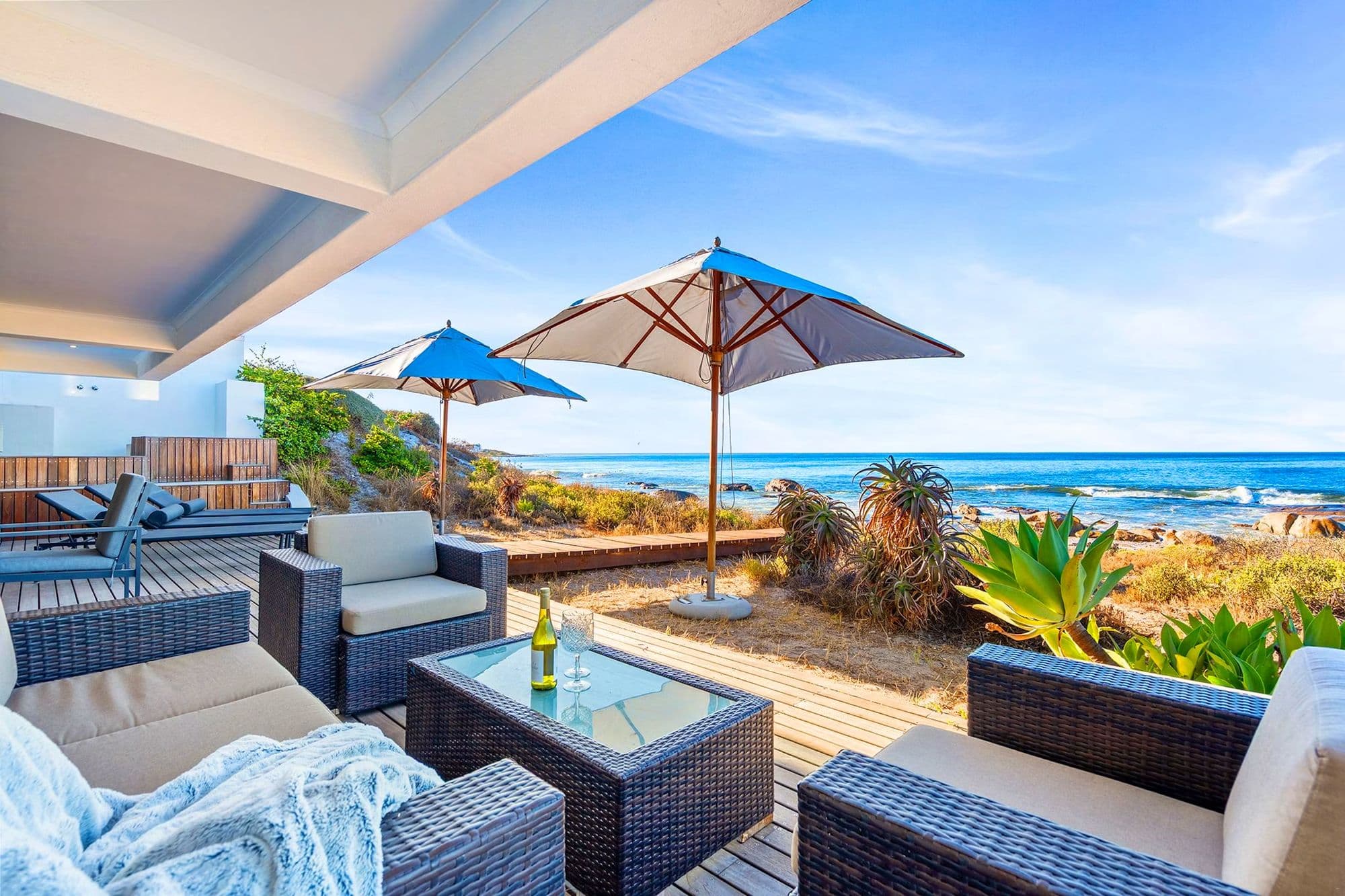A wraparound deck with umbrellas and loungers over the dunes